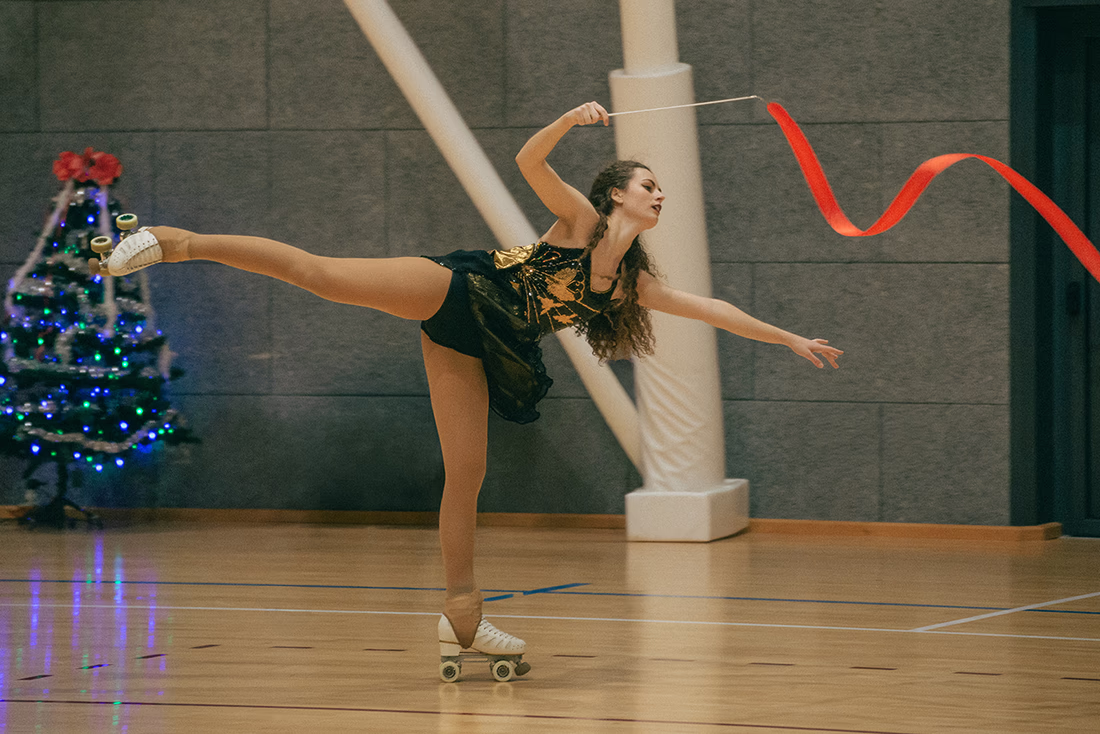 Photo of a female artistic skater performing with a gymnastics ribbon.
